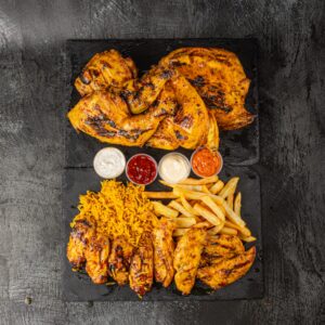 Family box with whole peri chicken, wings, rice, chips and dipping sauces at Bross Slice and Grill