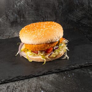 Crispy breaded veggie burger with lettuce and tomato in sesame bun at Bross Slice and Grill